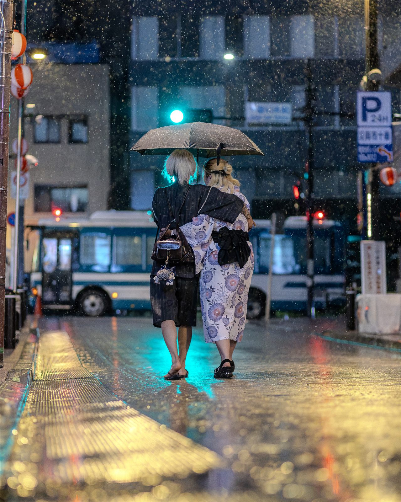 雨に濡れた路面と浴衣・傘の後ろ姿