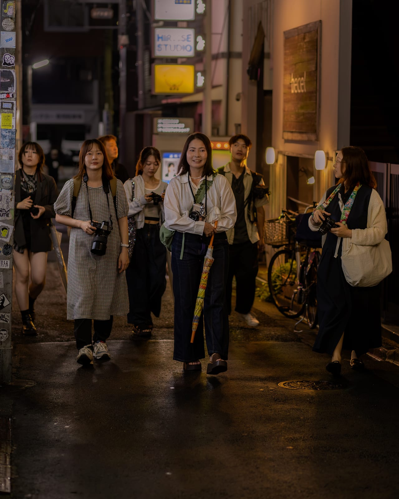 カメラを手に夜の下北沢の路地を歩く参加者たち