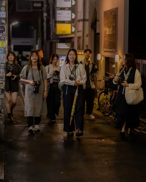 カメラを手に夜の下北沢の路地を歩く参加者たち