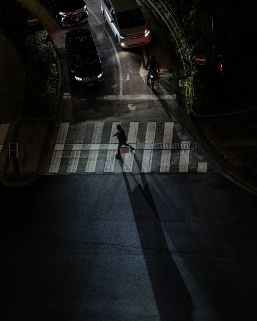 夜の交差点を渡る人と長く伸びた影のスナップ