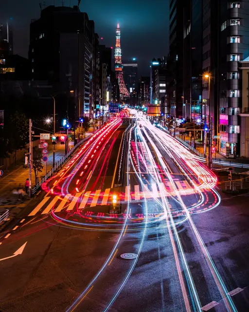 大通りに伸びる車の光跡の先にそびえる、ライトアップされた東京タワー（長時間露光）