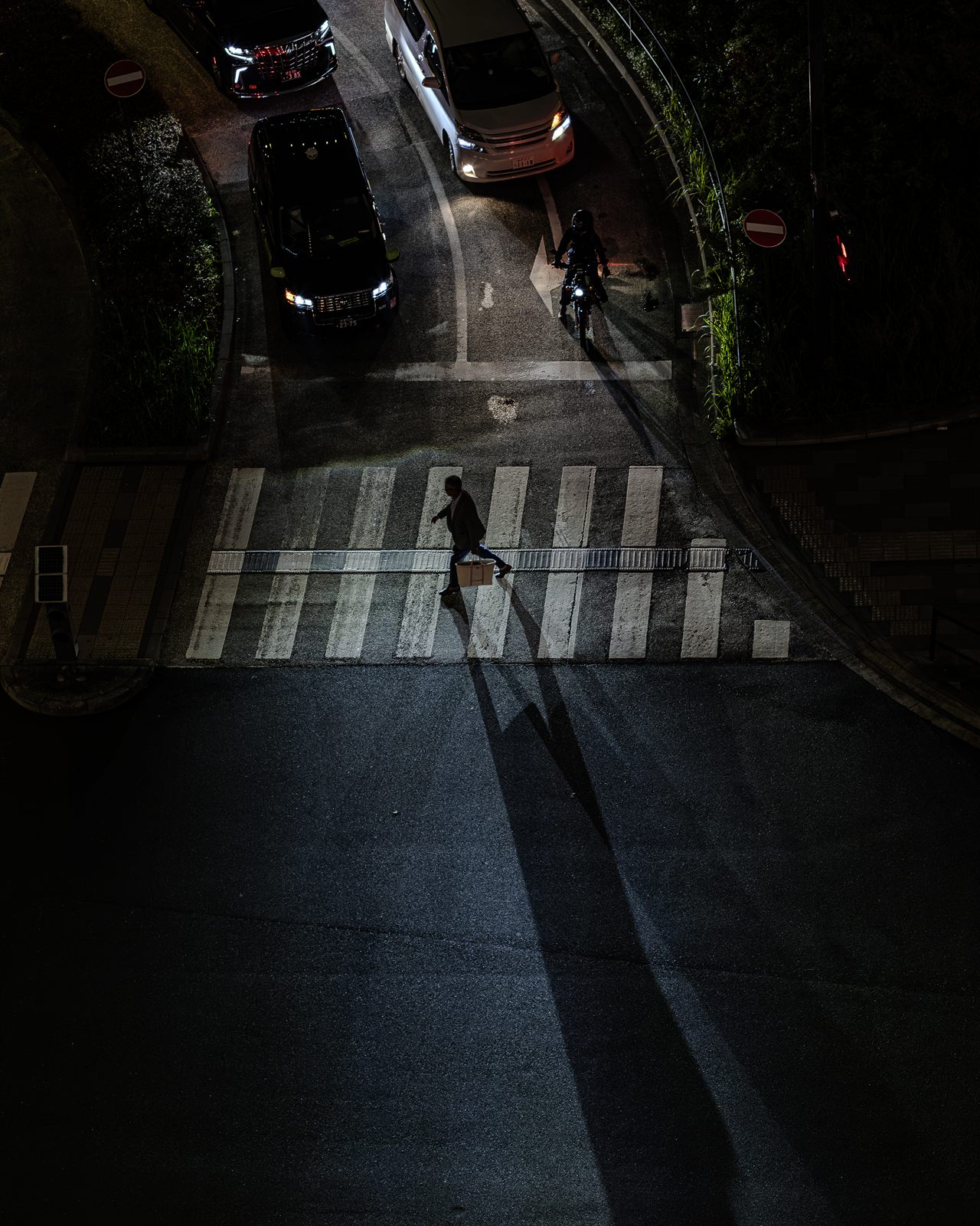 夜の交差点を渡る人と長く伸びた影のスナップ